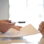 Crop businessman giving contract to woman to sign